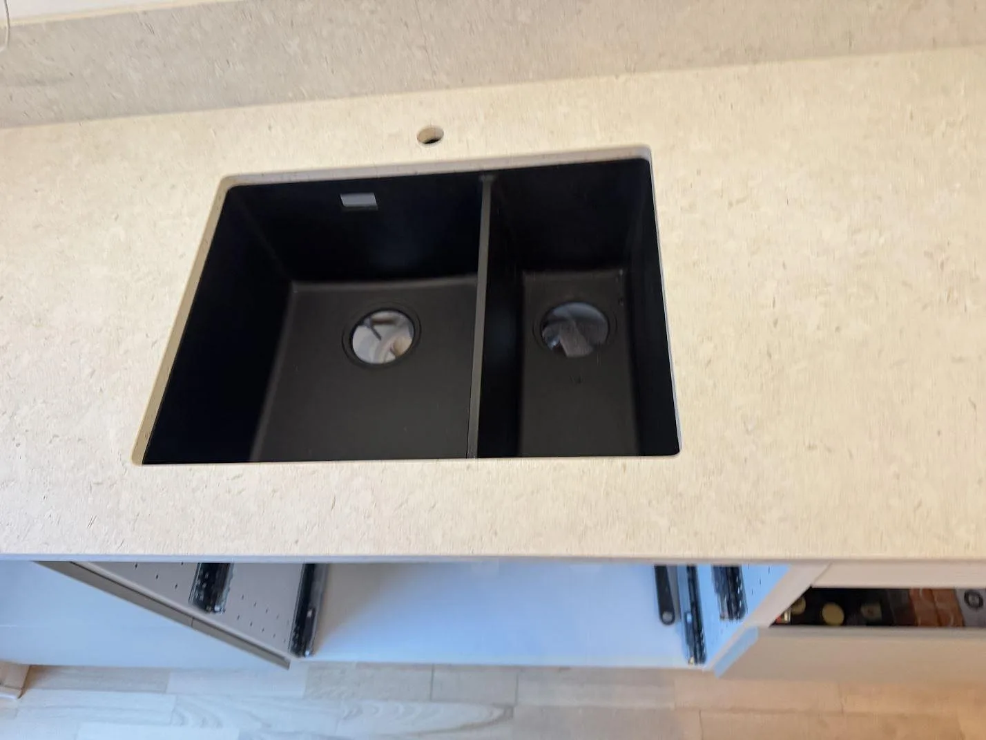 Detaljbild av svart diskho i köksbänkskiva av matt Dekton VK01 Nebbia i Lindome.