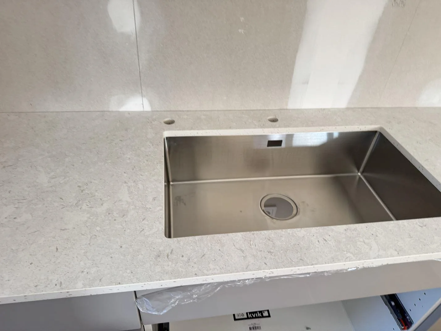 Närbild av köksbänkskiva i matt Dekton VK01 Nebbia med rostfri diskho och hål för blandare i Löddeköpinge.