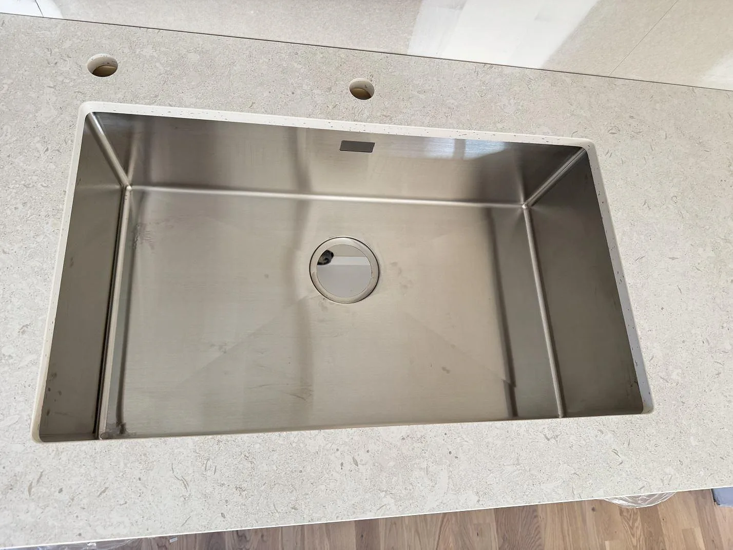 Toppvy av rostfri diskho i köksbänkskiva av matt Dekton VK01 Nebbia med två hål bakom hon i Löddeköpinge.