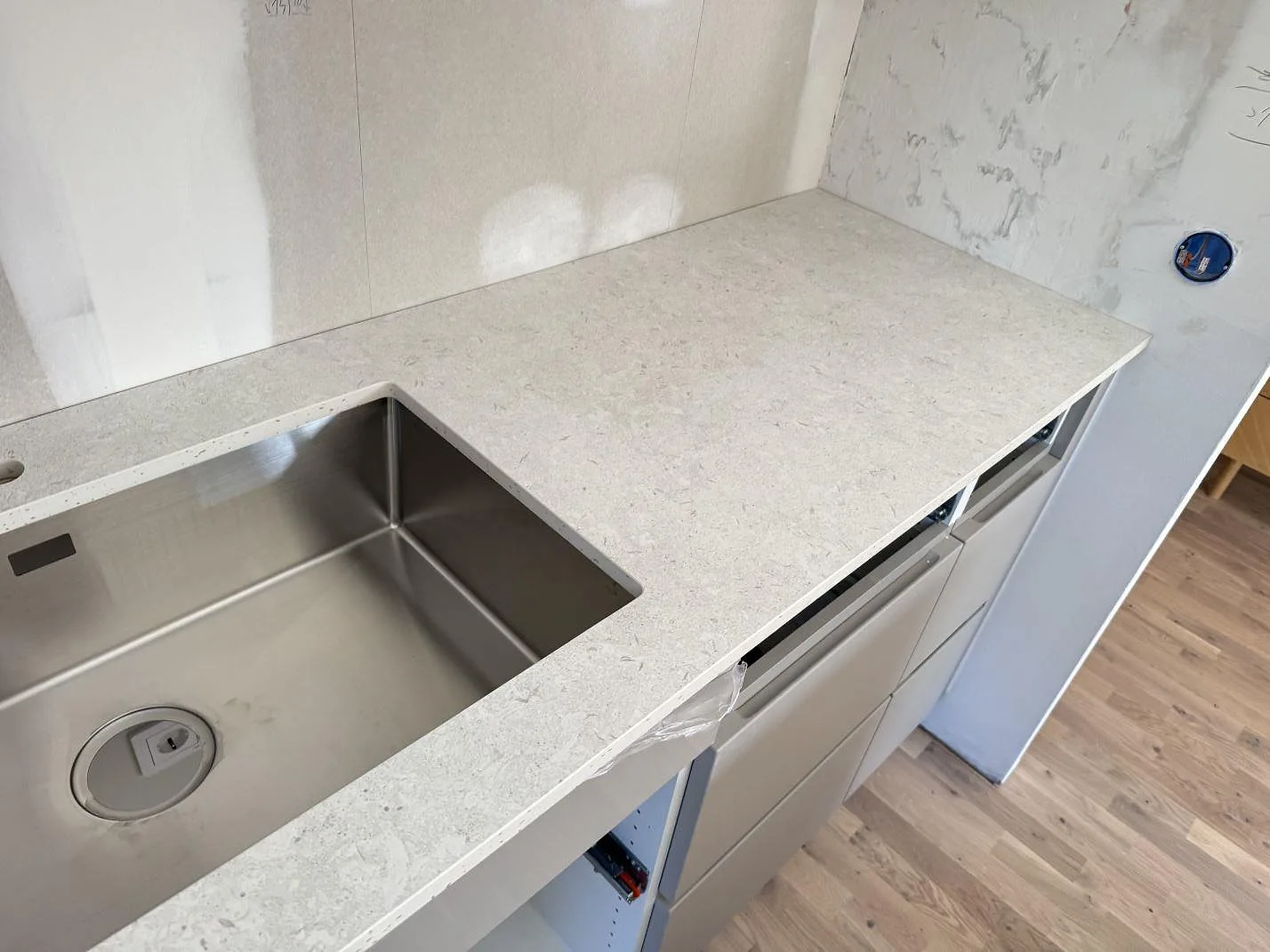 Köksbänkskiva i matt Dekton VK01 Nebbia med rostfri diskho, kranhål och ljus arbetsyta vid vägg i Löddeköpinge.