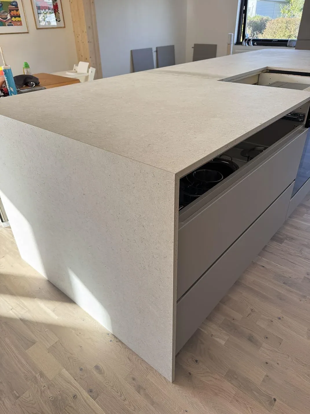 Sidovy av köksö i matt Dekton VK01 Nebbia med ljus keramisk yta och öppna stommar under montering i Löddeköpinge.