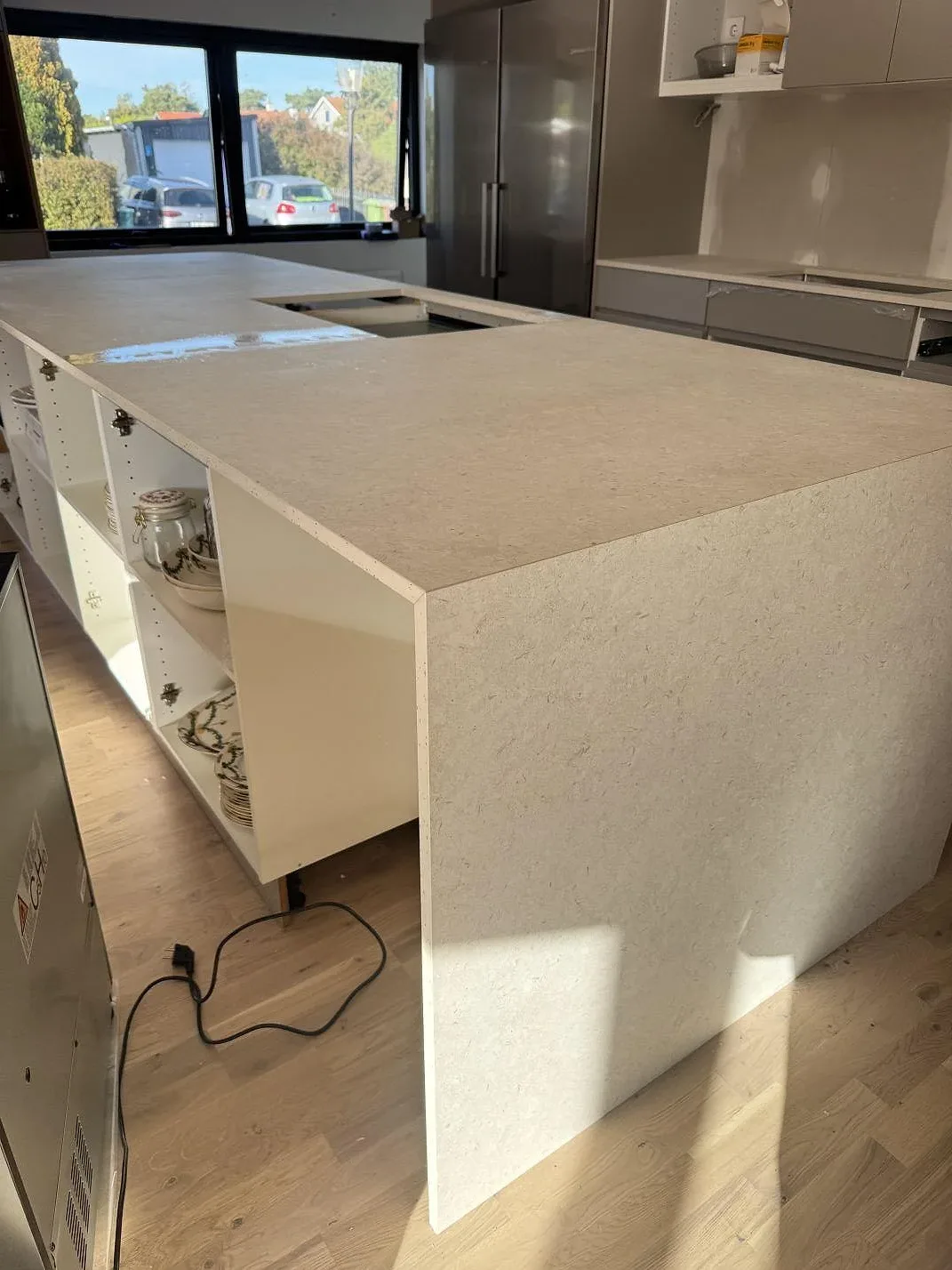 Närbild på ljus köksö i matt Dekton VK01 Nebbia med synlig kant och stenstruktur under montering i Löddeköpinge.
