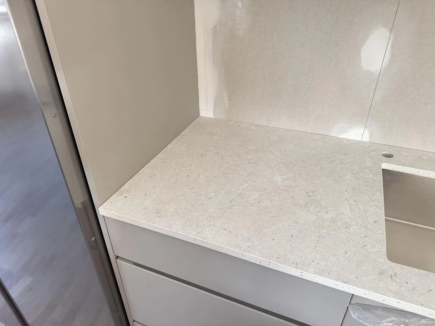Hörndetalj av matt Dekton VK01 Nebbia som köksbänkskiva med ljus struktur intill vägg och diskho i Löddeköpinge.