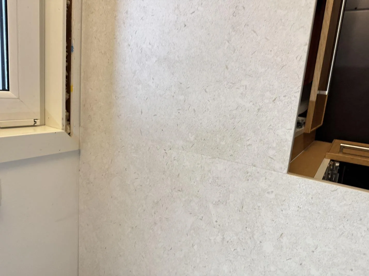 Närbild på mönstring och kantmöte i matt Dekton VK01 Nebbia vid fönster, köksbänkskiva i Löddeköpinge.