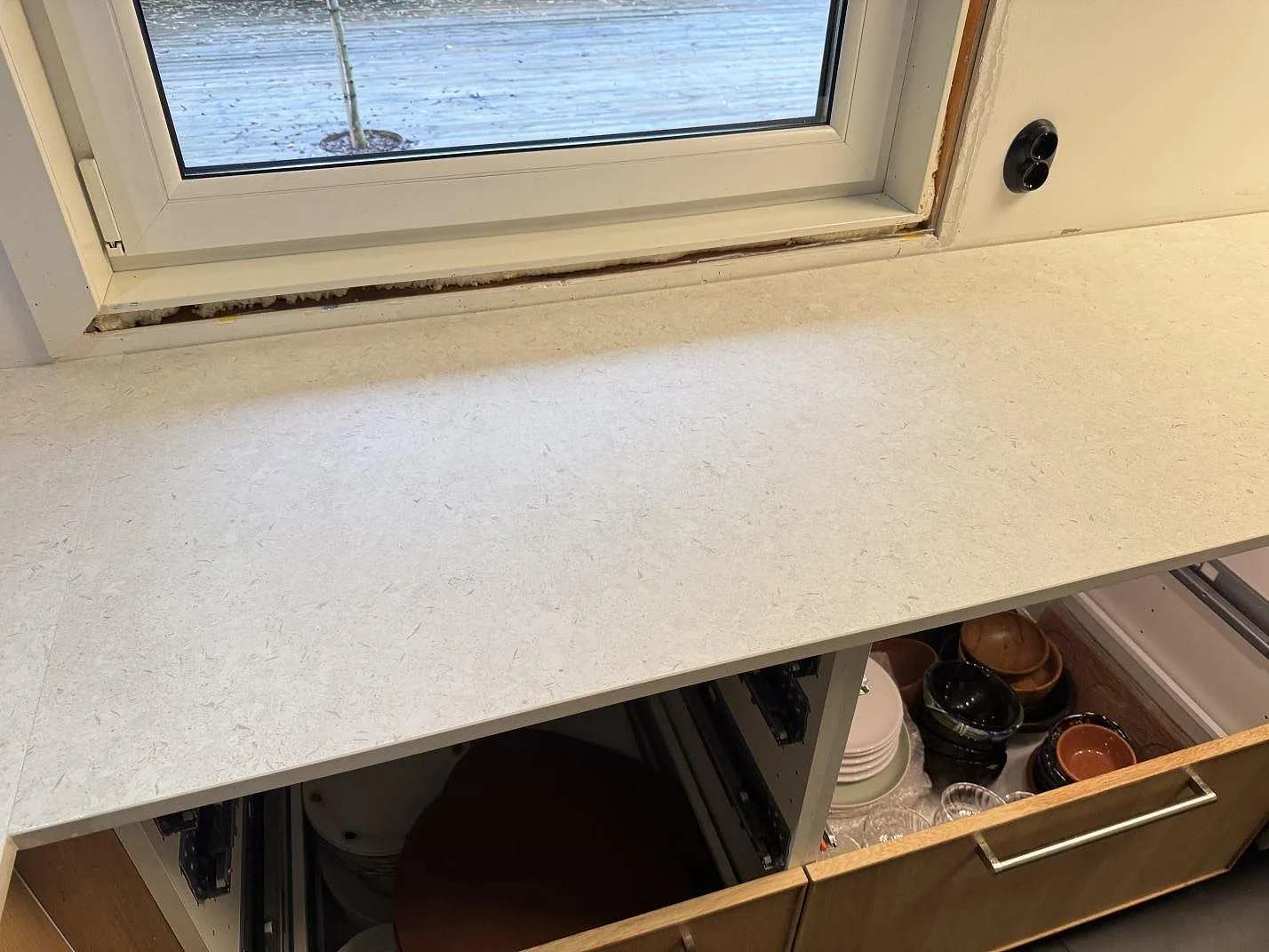 Rak arbetsyta under fönster i matt Dekton VK01 Nebbia, monterad som köksbänkskiva i Löddeköpinge.