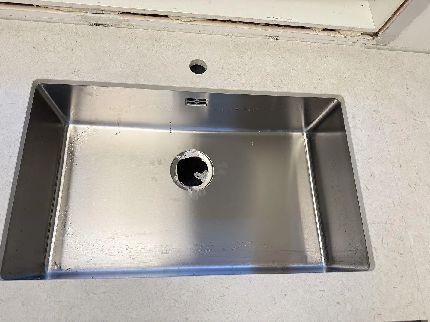 Toppsikt över rostfri diskho och kranhål i matt Dekton VK01 Nebbia, köksbänkskiva i Löddeköpinge.