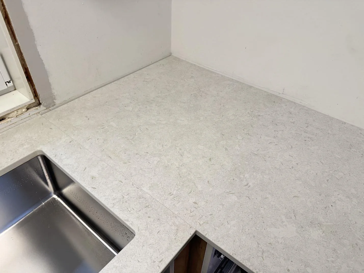 Detalj av hörn och arbetsyta i matt Dekton VK01 Nebbia med diskho intill, monterat i kök i Löddeköpinge.