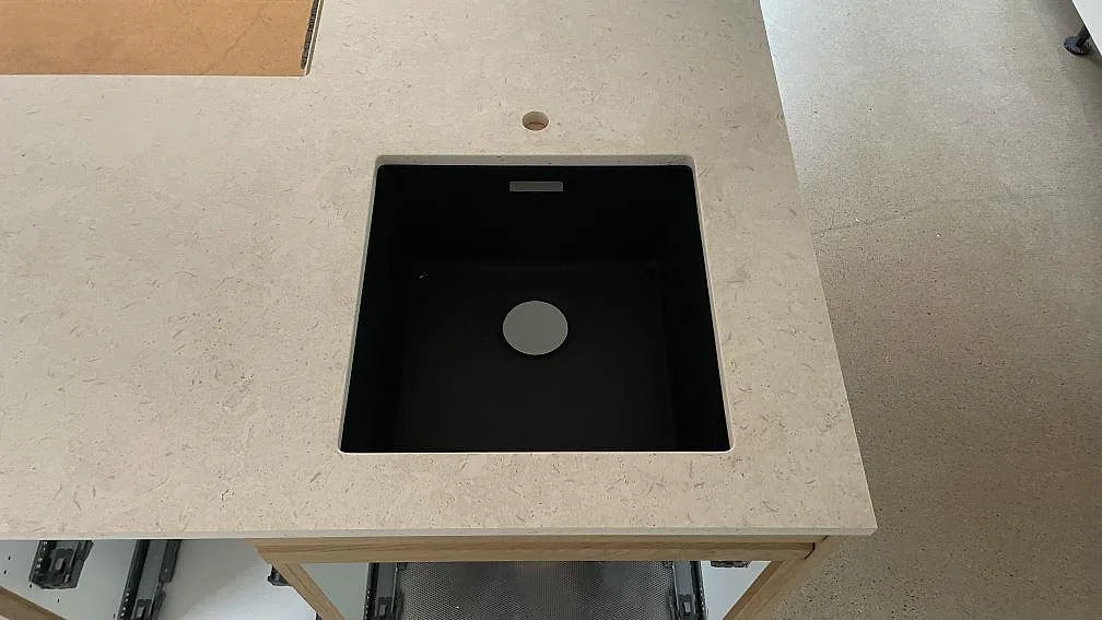 Detalj av köksbänkskiva i matt Dekton VK01 Nebbia med svart diskho och ljus stenstruktur i Malmö.