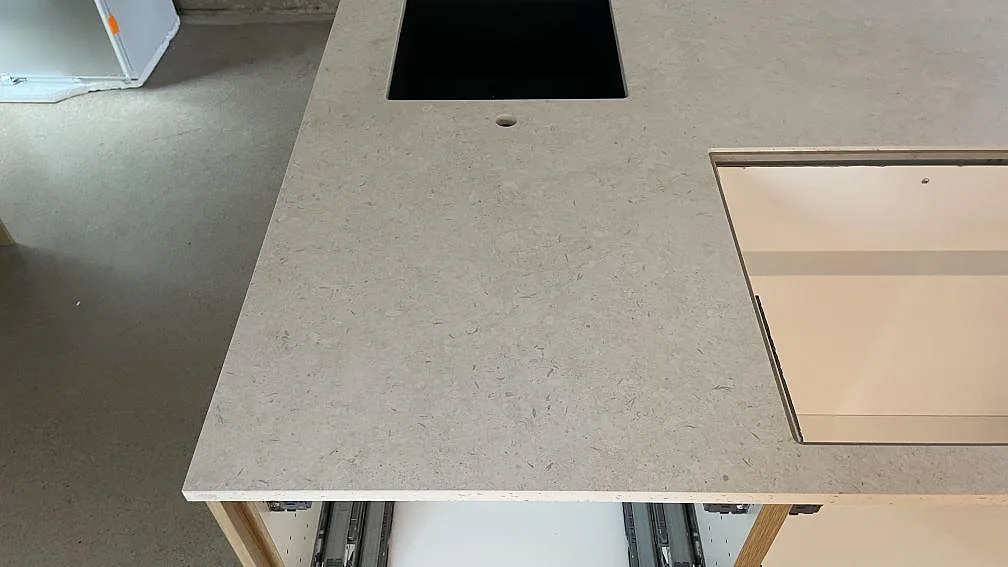 Närbild av ljus matt Dekton VK01 Nebbia med urtag i köksö och öppna köksstommar i Malmö.