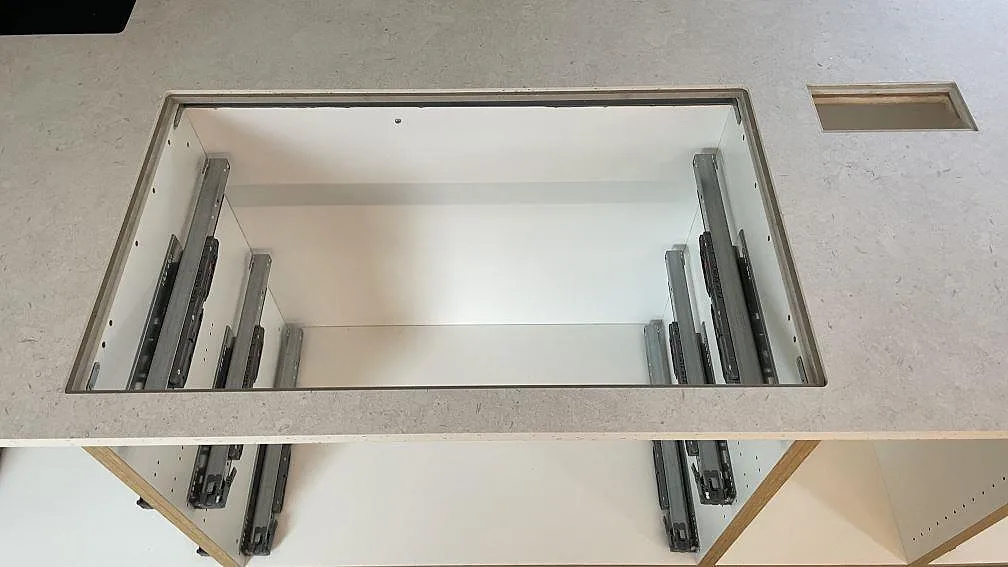Detalj av installerad Dekton VK01 Nebbia runt ett stort rektangulärt urtag i köksön under montering i Malmö.