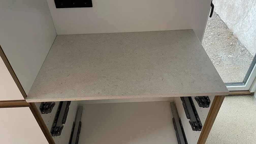 Sidobänk i matt Dekton VK01 Nebbia monterad vid fönster i ett kök i Malmö.