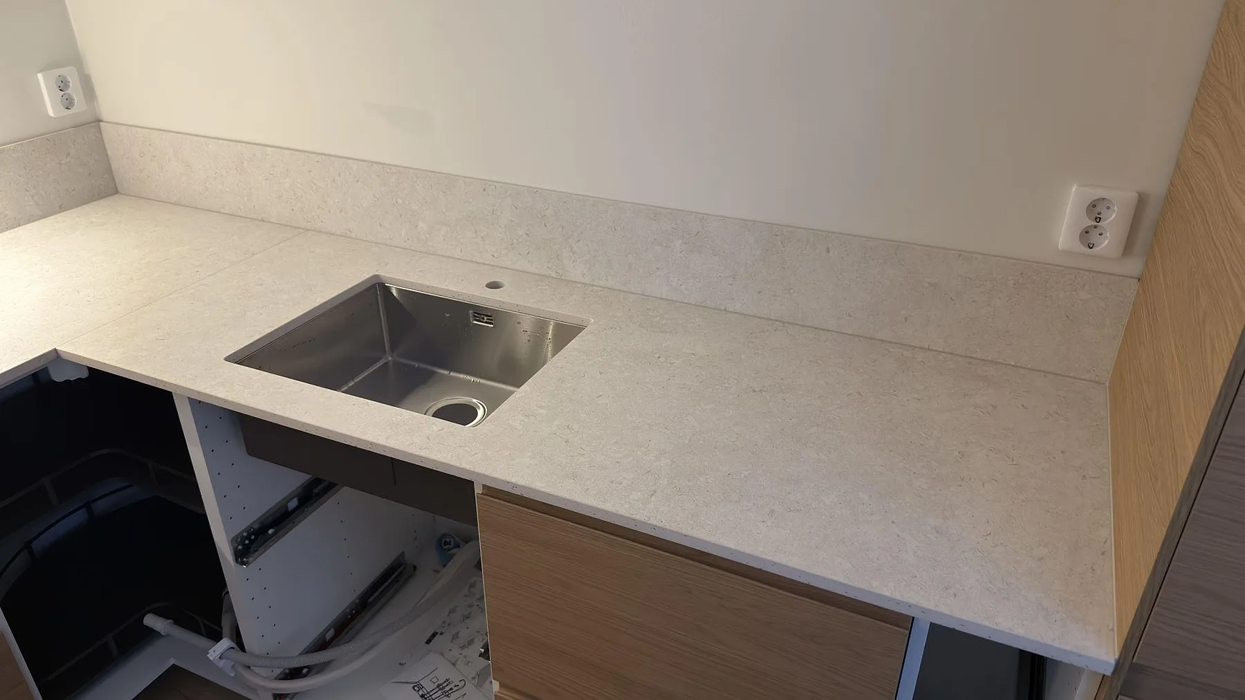 Matt köksbänkskiva i Dekton VK01 Nebbia med diskho och stänkkant i kök under montering i Solna.