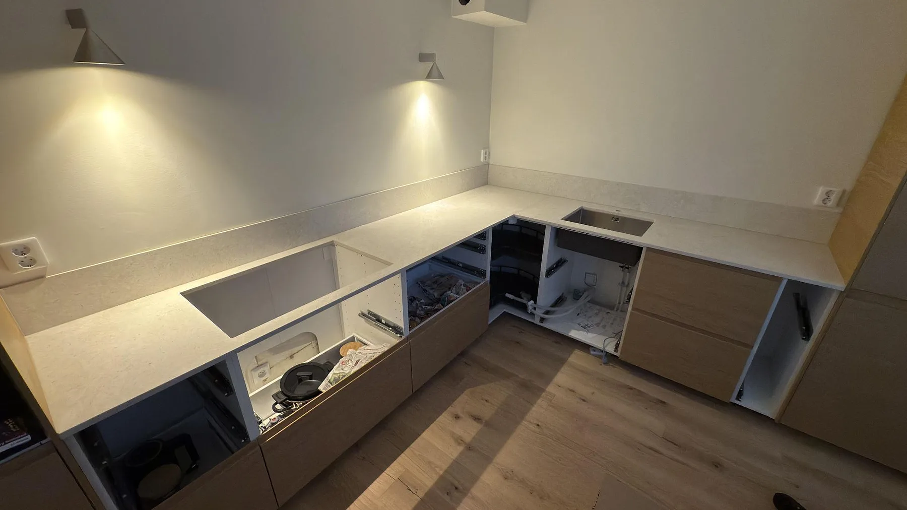 L-formad keramisk köksbänkskiva i matt Dekton VK01 Nebbia med stänkkant, diskho och hälluttag i ett kök i Solna.