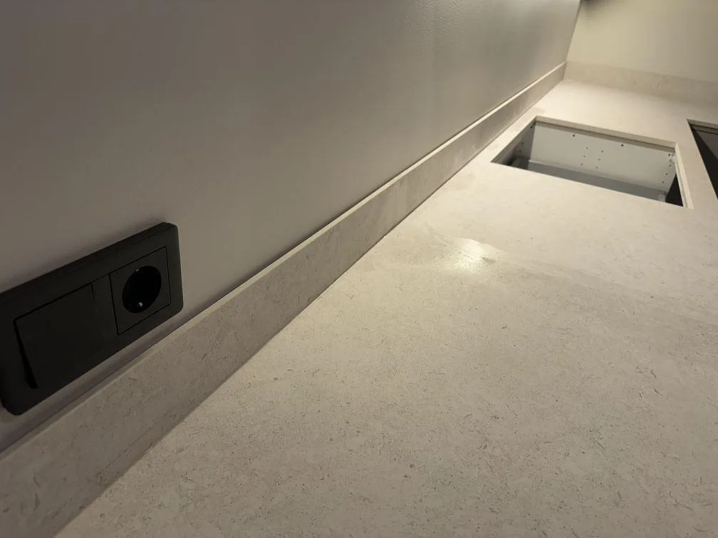 Lång bänkyta i matt Dekton VK01 Nebbia med stänkskydd, vägguttag och synlig stenstruktur i Trelleborg.