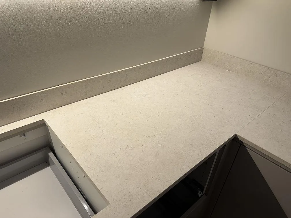 Detalj av hörn och urtag i matt Dekton VK01 Nebbia med stänkskydd längs väggen i ett kök i Trelleborg.