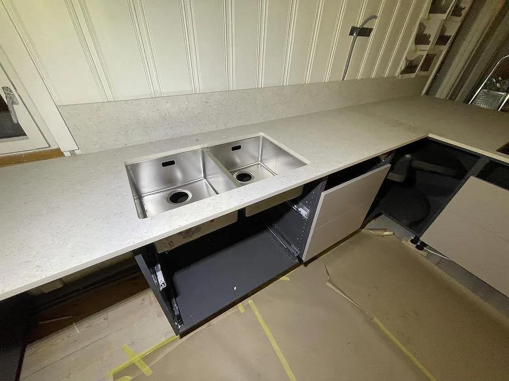 Underlimmad dubbel rostfri diskho i en matt Dekton VK01 Nebbia köksbänkskiva längs väggsidan i ett kök i Trosa.