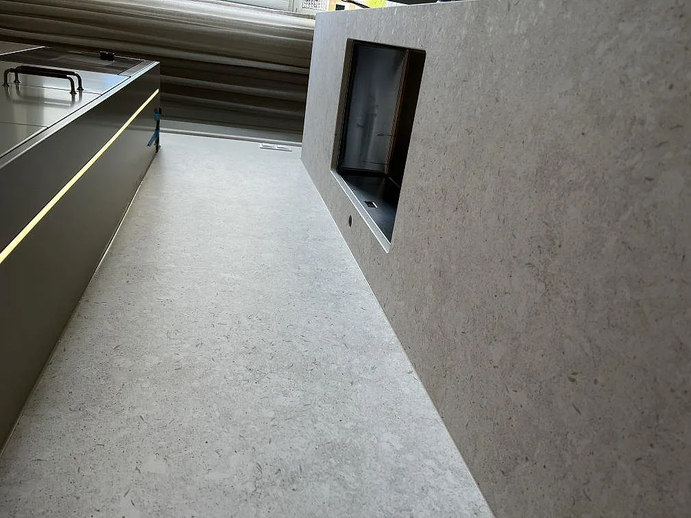 Detalj av matt Dekton VK01 Nebbia bänkskiva med rostfri diskho och ljus stenstruktur i Värnamo.
