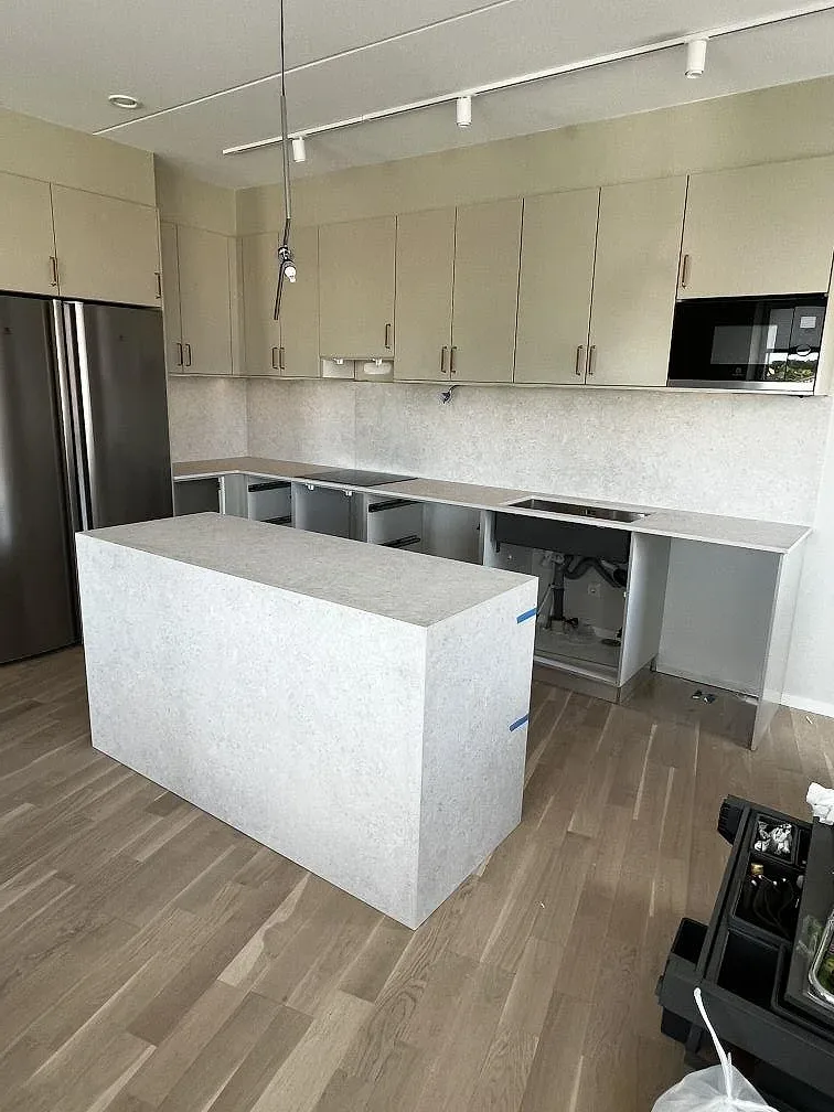 Köksö och köksbänkskiva i matt Dekton VK01 Nebbia med vattenfallssida i ett kök med trägolv i Värnamo.