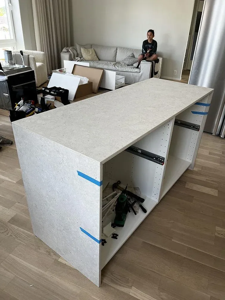 Köksö i matt Dekton VK01 Nebbia med öppna vita stommar och monteringsverktyg i ett kök i Värnamo.