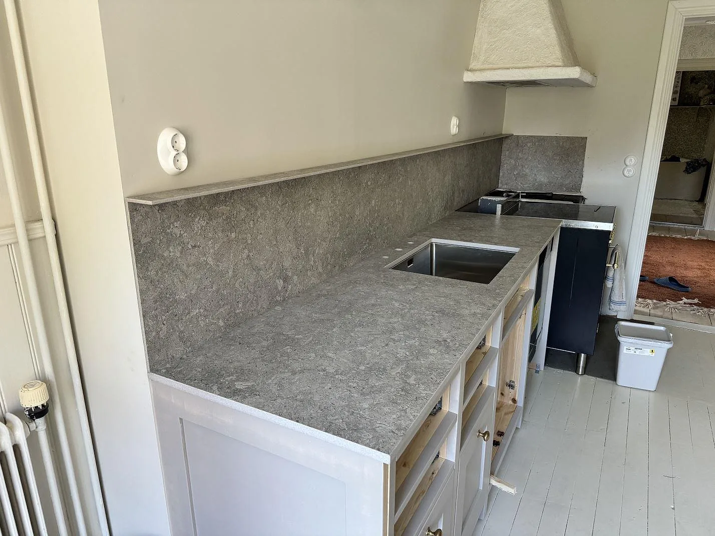 Köksbänkskiva i matt Dekton VK03 Grigio, keramik, med grått stänkskydd, diskho och spisdel i ett kök i Alingsås.