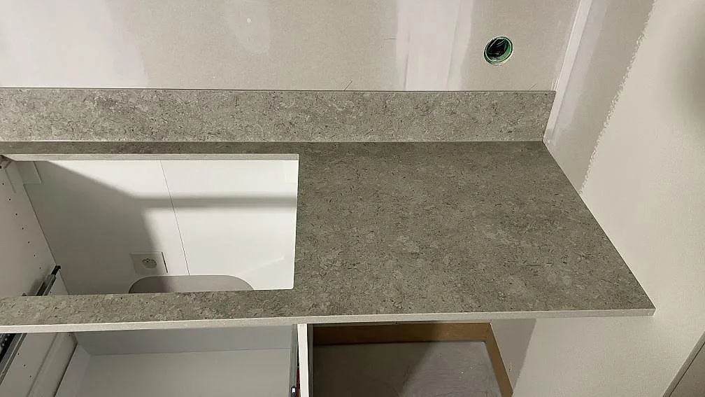 Hällöppning och arbetsyta i matt Dekton VK03 Grigio med låg grå stänkkant i ett kök i Dalby.