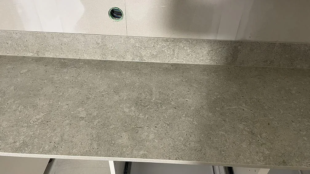 Rak arbetsyta i matt Dekton VK03 Grigio med spräcklig grå struktur och stänkskydd i ett kök i Dalby.