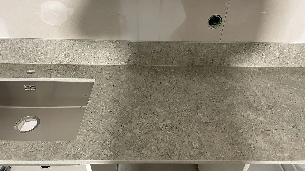 Detalj av diskho, kranhål och grå Dekton VK03 Grigio yta med stänkskydd i ett kök i Dalby.