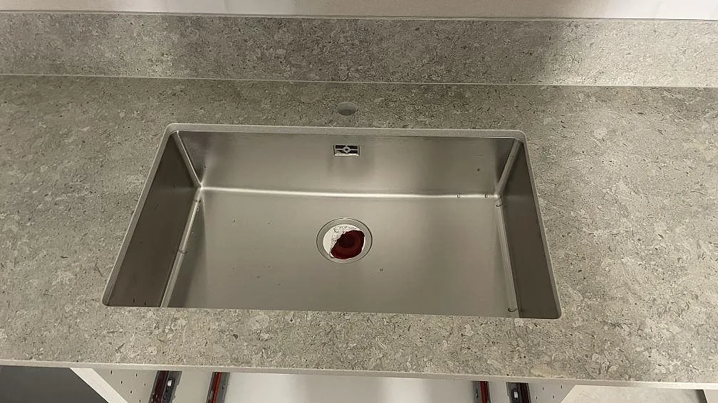 Närbild på rostfri diskho i en matt Dekton VK03 Grigio köksbänkskiva med grå stänkkant i Dalby.