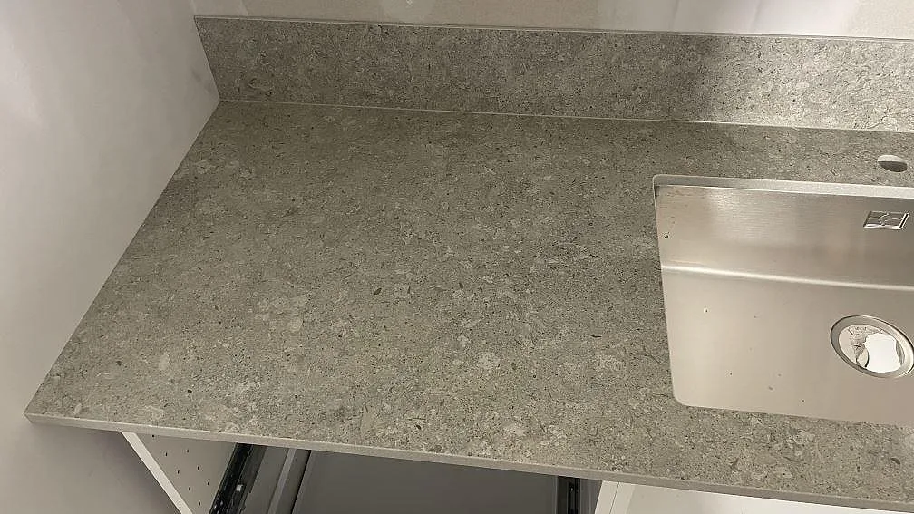 Sidovy av matt Dekton VK03 Grigio bänkskiva med rostfri diskho och vänster arbetsyta i ett kök i Dalby.