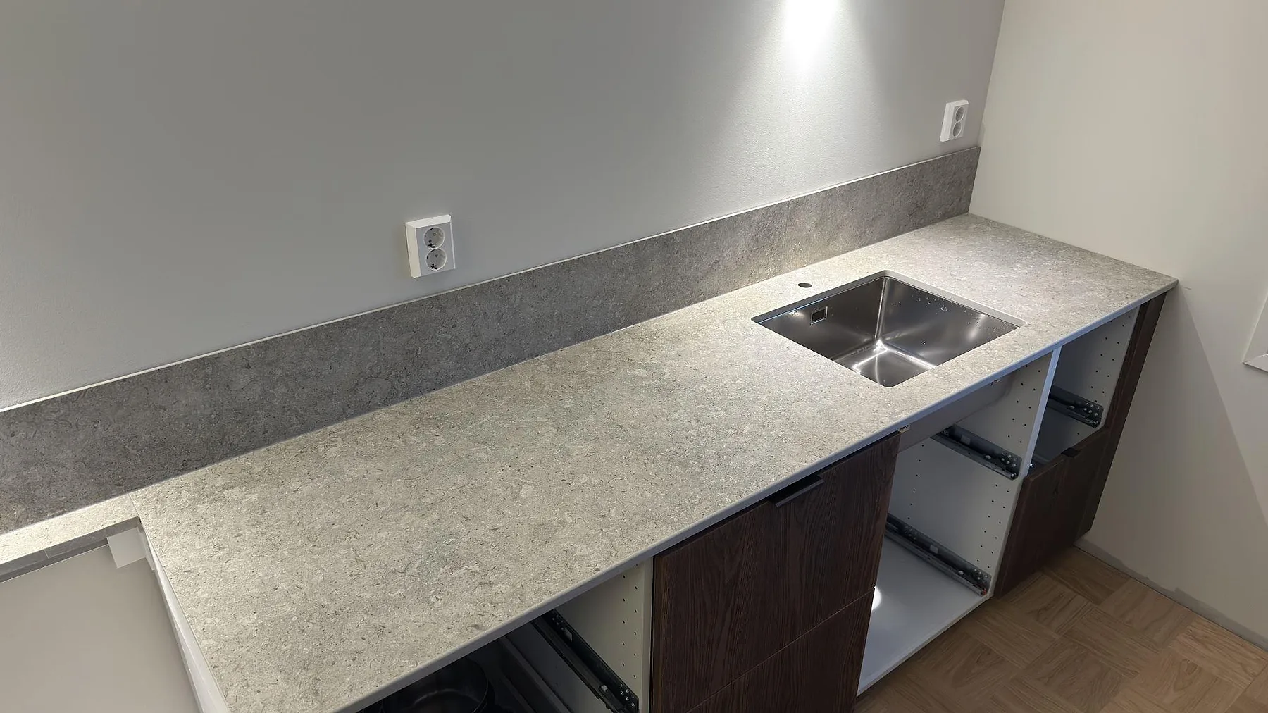 Diskbänksrad i matt Dekton VK03 Grigio med rostfri diskho och grått stänkskydd i ett kök i Eskilstuna.