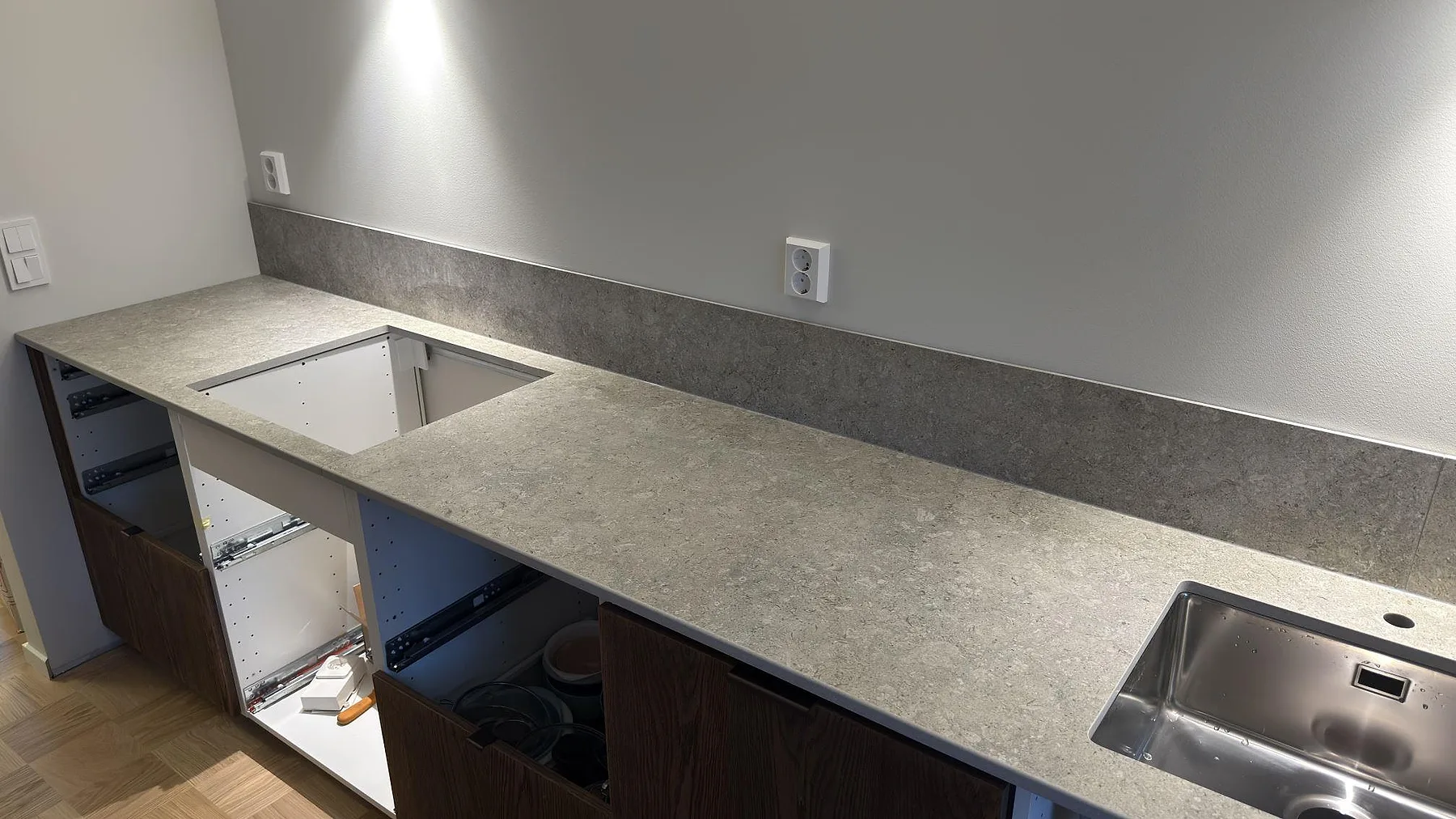 Bänkskiva i matt Dekton VK03 Grigio med hälluttag, rostfri diskho och grått stänkskydd i Eskilstuna.