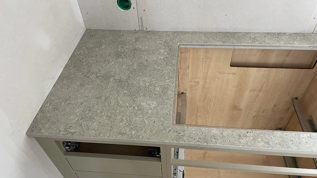 Närbild på matt Dekton VK03 Grigio som köksbänkskiva med förberedd hällöppning och öppen trästomme i Fjärås.