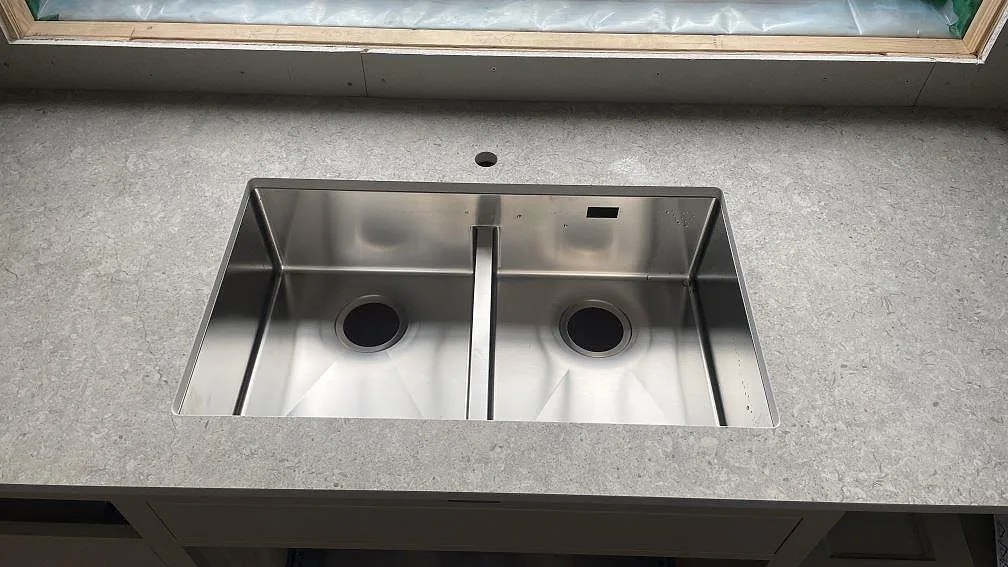 Rostfri dubbel diskho i en matt köksbänkskiva i Dekton VK03 Grigio vid fönster i Fjärås.