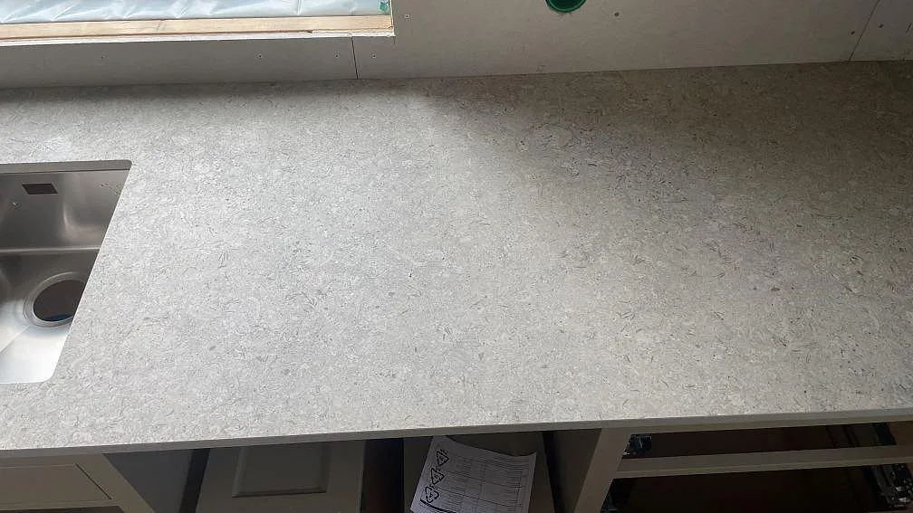 Lång arbetsyta i matt Dekton VK03 Grigio bredvid diskhon i ett kök under montering i Fjärås.