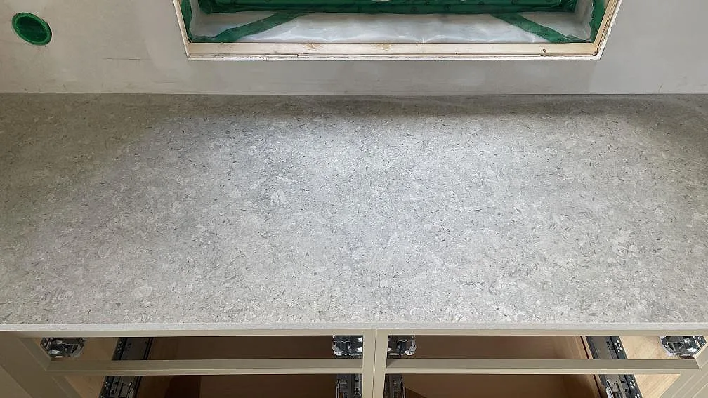 Rak väggbänk i matt Dekton VK03 Grigio under köksfönster med öppna stommar i Fjärås.