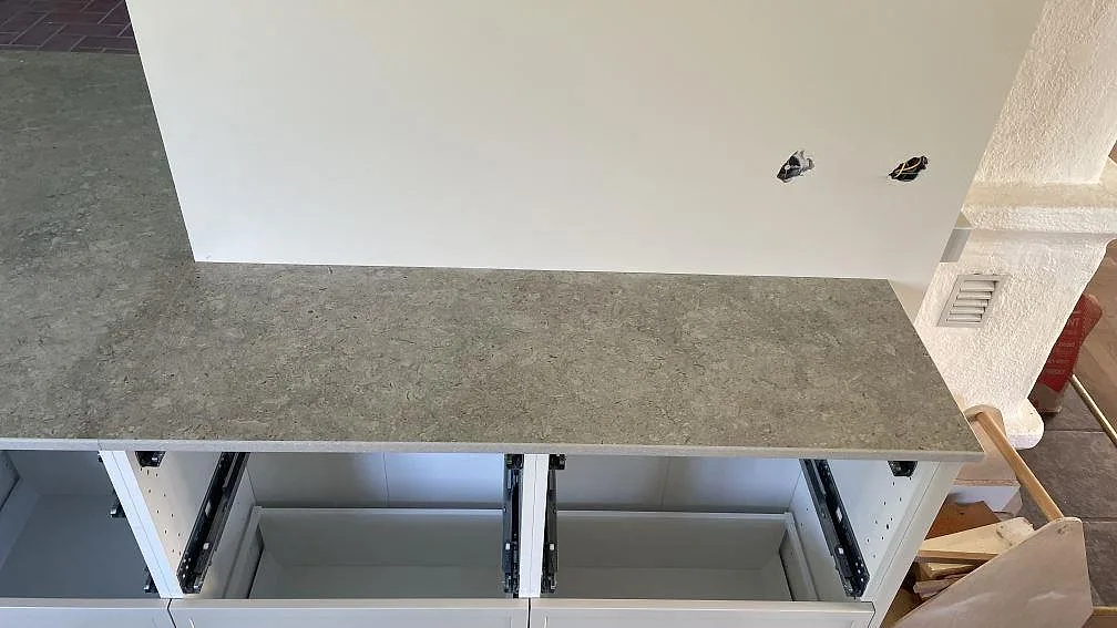 Sidobänk i matt Dekton VK03 Grigio vid vägg med eluttag under köksmontering i Kävlinge.