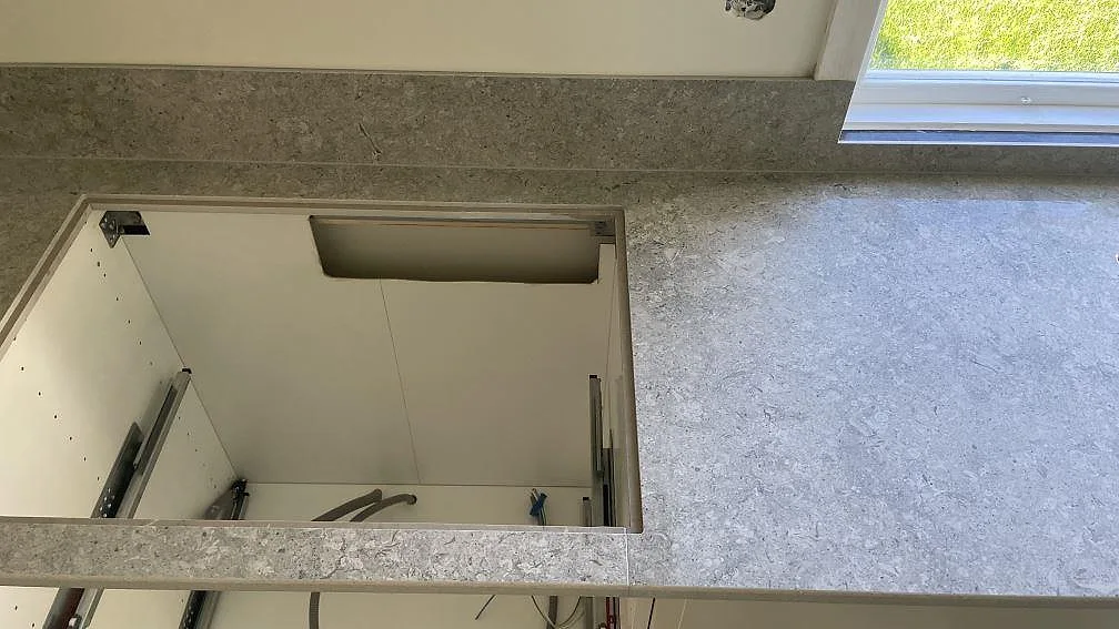 Diskbänksdel i matt grå Dekton VK03 Grigio med stänkkant och fönsterljus i ett kök i Kävlinge.