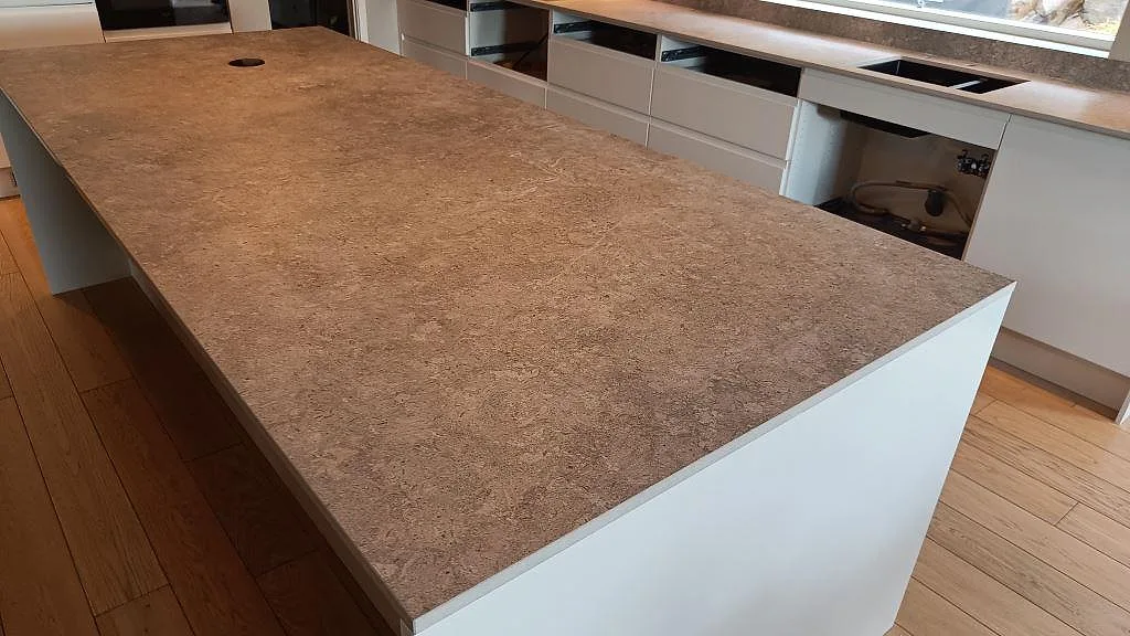 Närbild av stor köksö i matt Dekton VK03 Grigio med taupegrå betongstruktur i ett kök i Kullavik.