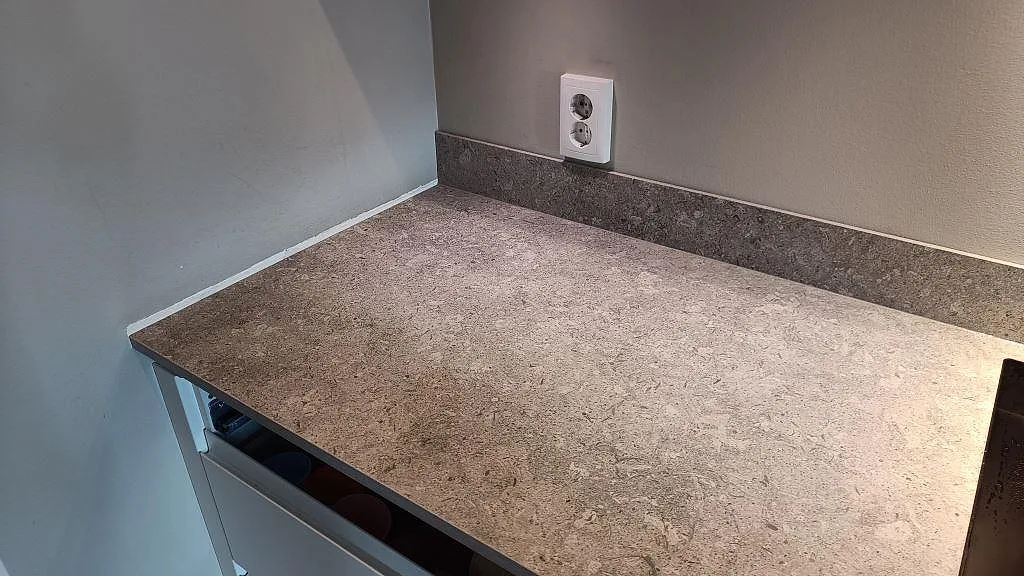 Rak köksbänkskiva i matt Dekton VK03 Grigio med låg stänkkant och vägguttag i Kullavik.