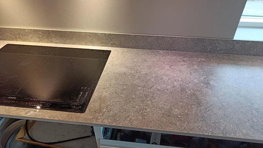 Köksbänkskiva i matt Dekton VK03 Grigio med induktionshäll, fönster och sammanhängande arbetsyta i Kullavik.