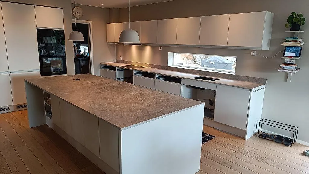 Köksbänkskiva i matt Dekton VK03 Grigio med stor köksö, pendellampor och vit skåpsinredning i Kullavik.