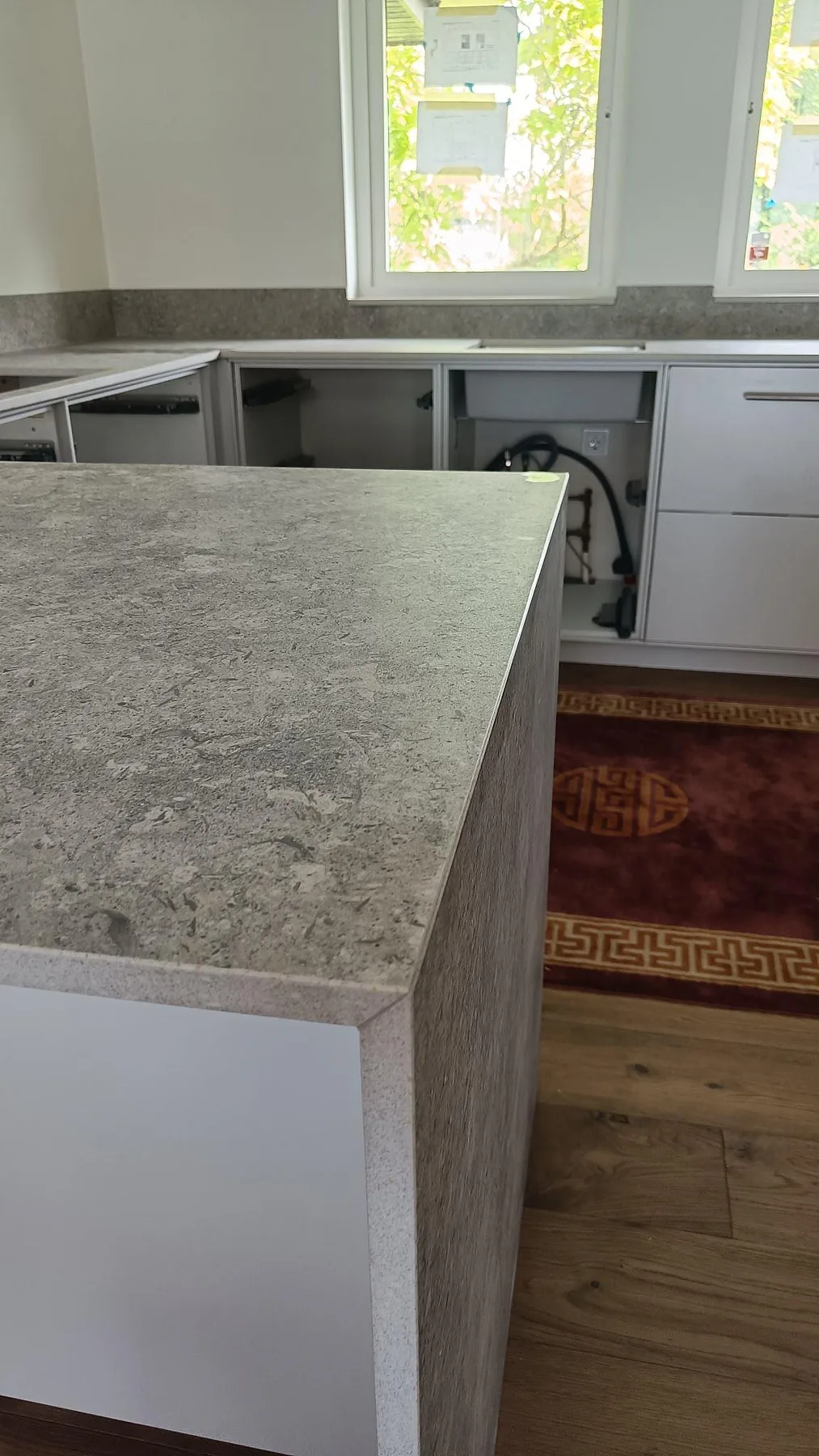 Köksbänkskiva i grå keramik, Dekton VK03 Grigio i matt finish, framför fönster och öppna köksstommar i Malmö.
