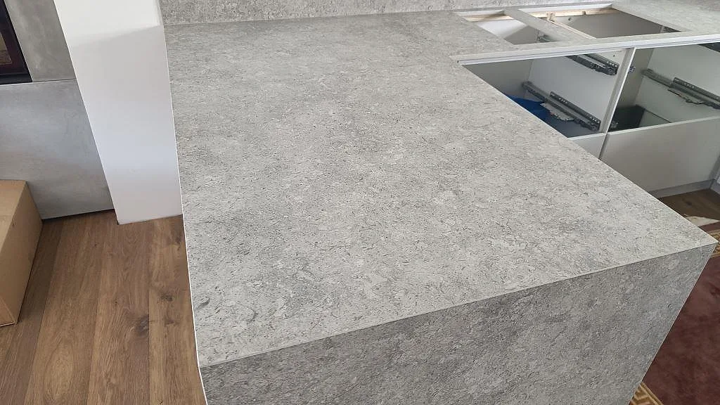 Köksbänkskiva i matt Dekton VK03 Grigio med uppvikt stänkkant och förberedda urtag i ett kök i Malmö.