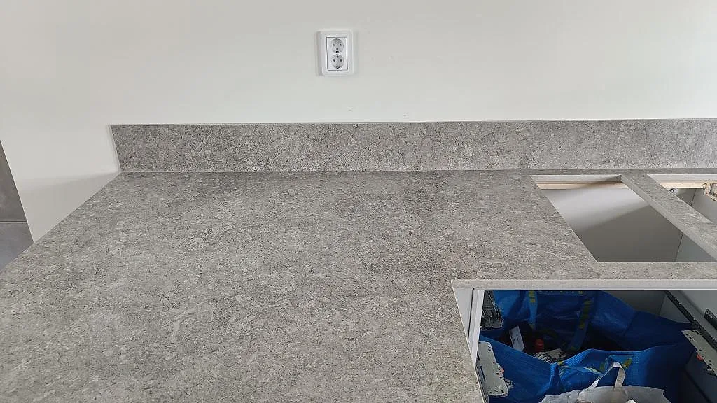 Närbild på matt Dekton VK03 Grigio som köksbänkskiva med stänkkant och rektangulära urtag i Malmö.