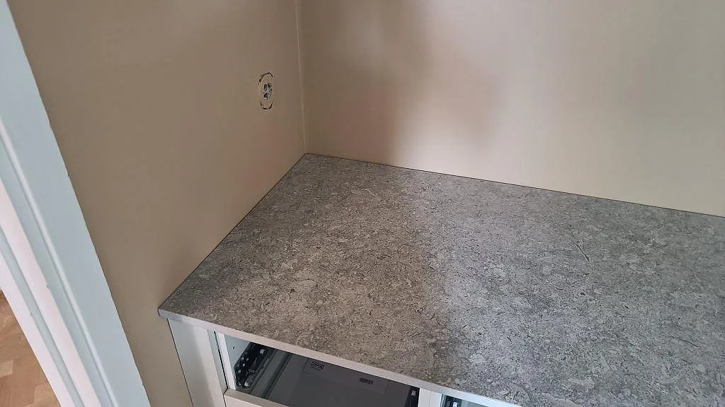 Sidoyta med installerad köksbänkskiva i matt Dekton VK03 Grigio mot vägg i ett kök i Malmö.