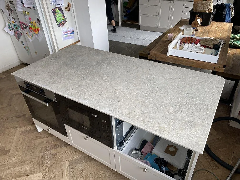 Köksö i matt Dekton VK03 Grigio, grå keramisk bänkskiva med tunn kant och rundat hörn under montering i Malmö.