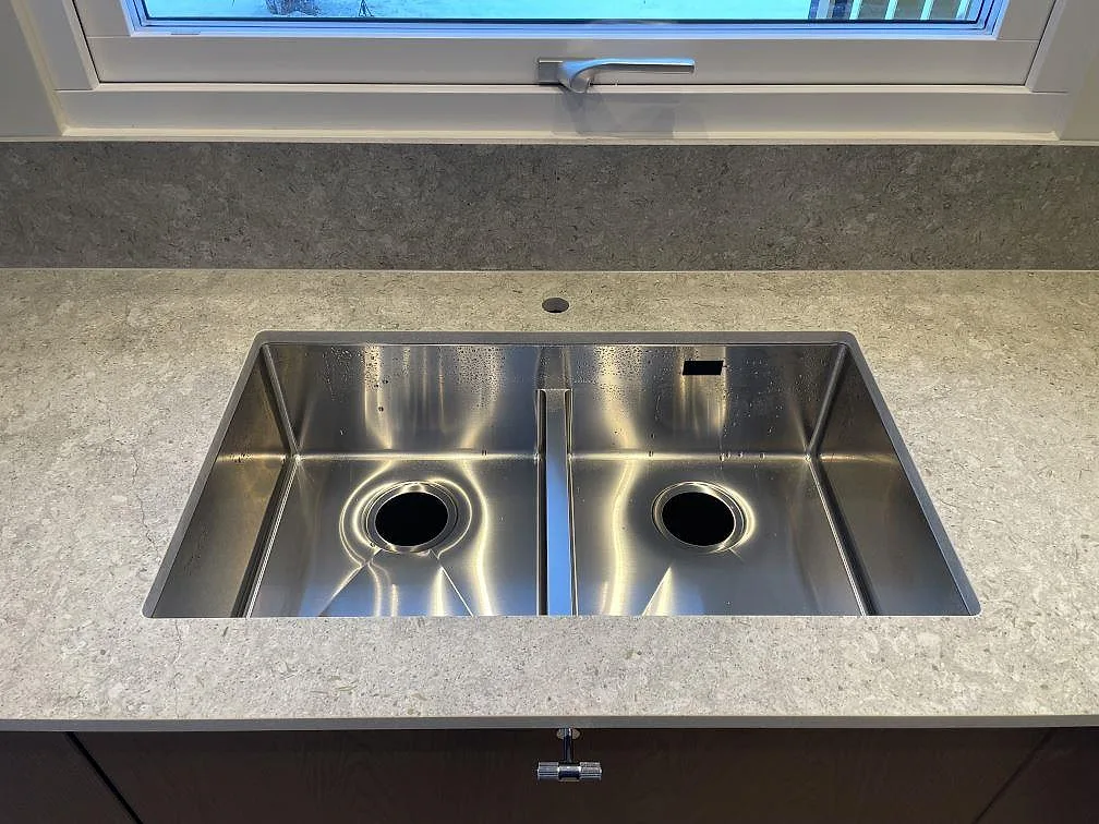 Underlimmad rostfri diskho med dubbla hoar i matt grå Dekton VK03 Grigio bänkskiva i ett kök i Vreta Kloster.