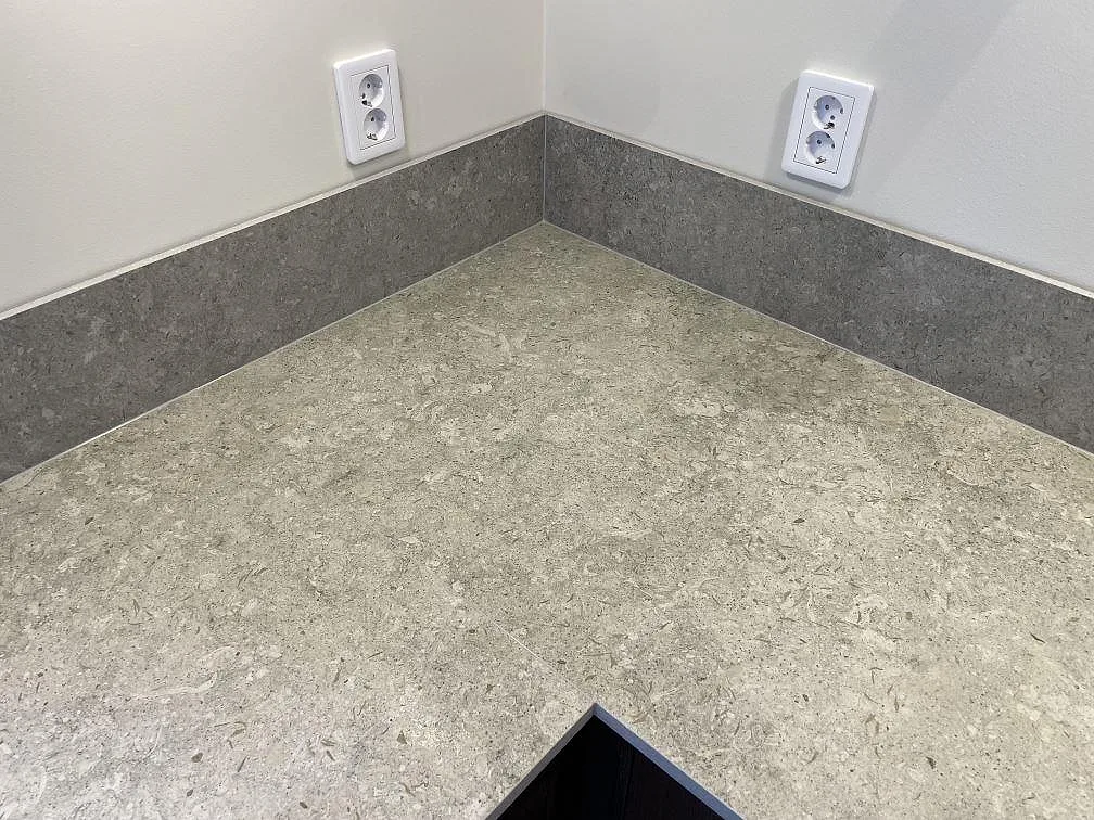 Detalj av matt grå Dekton VK03 Grigio bänkskiva med uppvikt stänkkant i ett kök i Vreta Kloster.