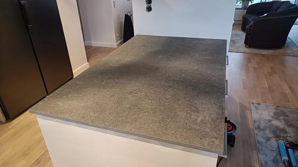 Köksö i matt Dekton Vk04 Grafite sedd från sidan, med stor sammanhållen arbetsyta i köket i Ängelholm.