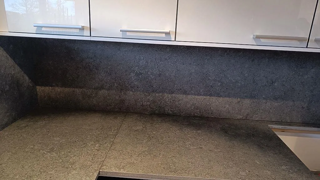 Detalj av matt Dekton Vk04 Grafite på bänkskiva och stänkskydd under överskåp i ett kök i Ängelholm.